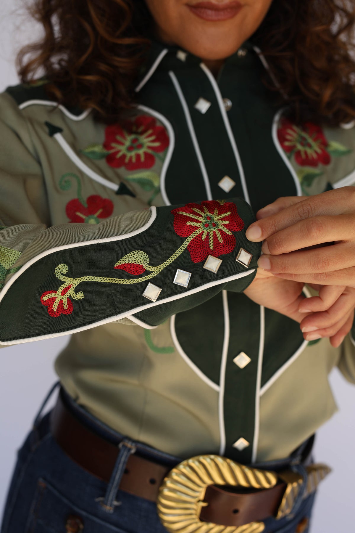 Close-up of the H Bar C Santa Ana green western shirt with red floral yoke embroidery and gold western belt buckle, vintage inspired western wear.