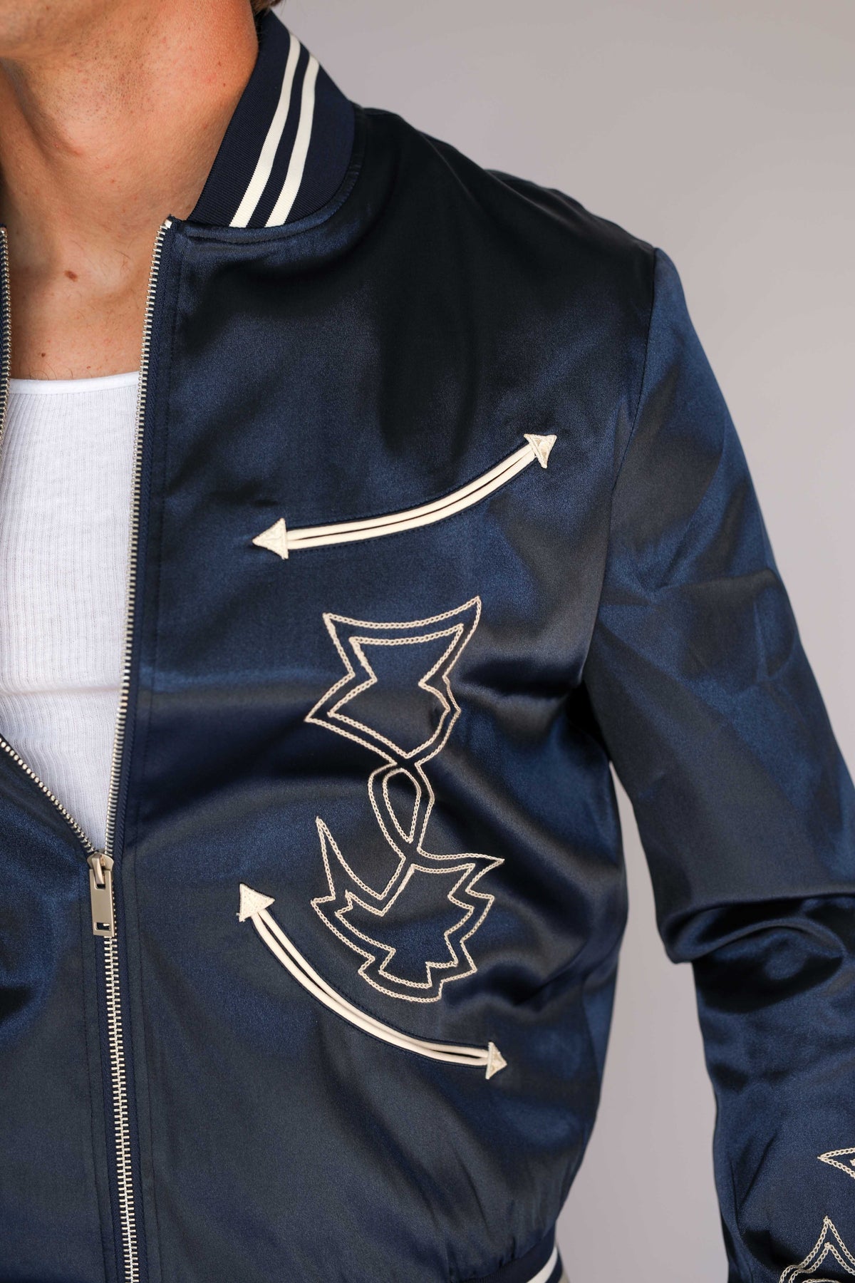 Side view of the H Bar C Odessa navy satin jacket showing cream chain stitch embroidery on the sleeve, vintage western wear detail.