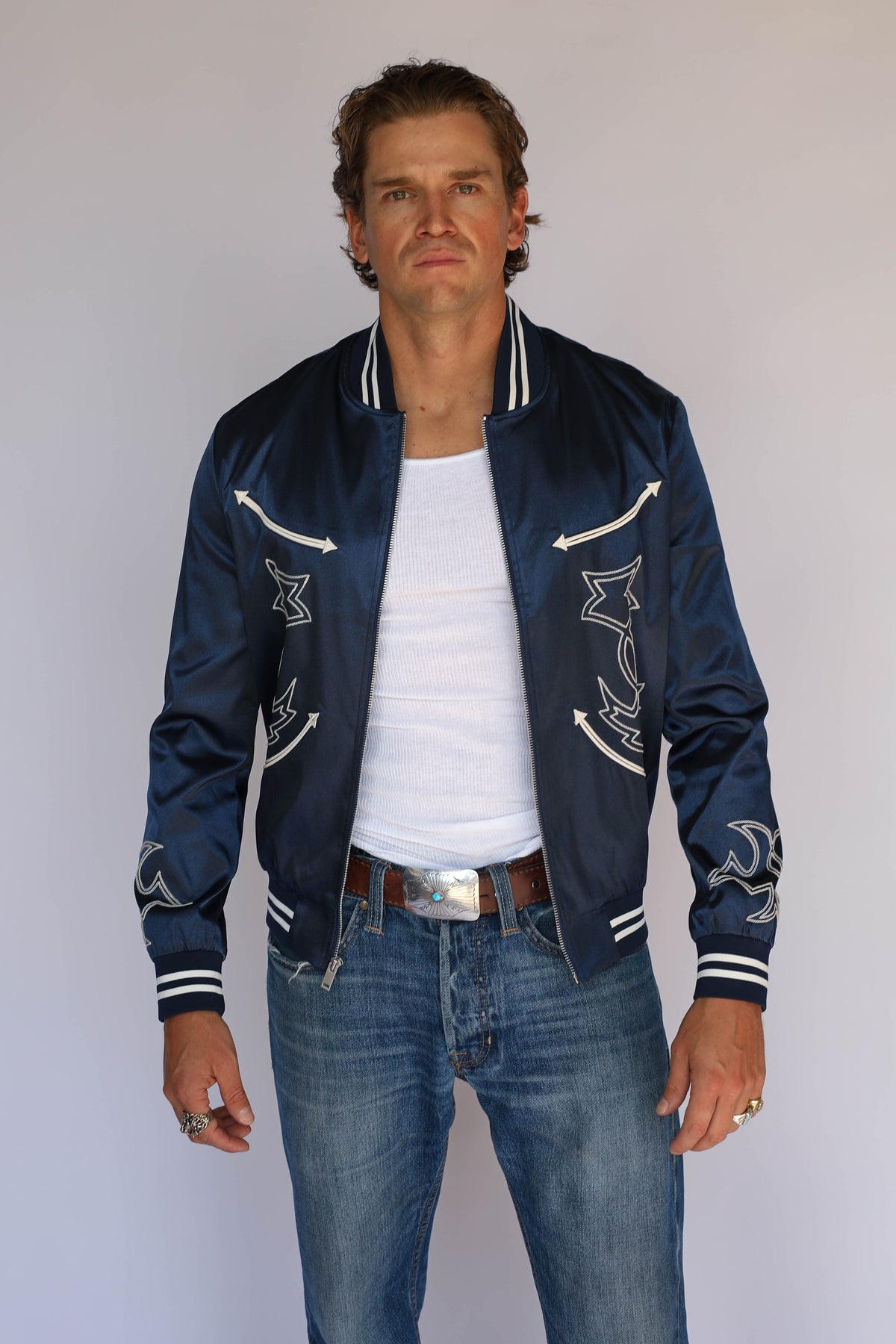 Front view of the open H Bar C Odessa navy satin tour jacket over a white tank, vintage inspired western wear with cream chain stitch embroidery and arrows.