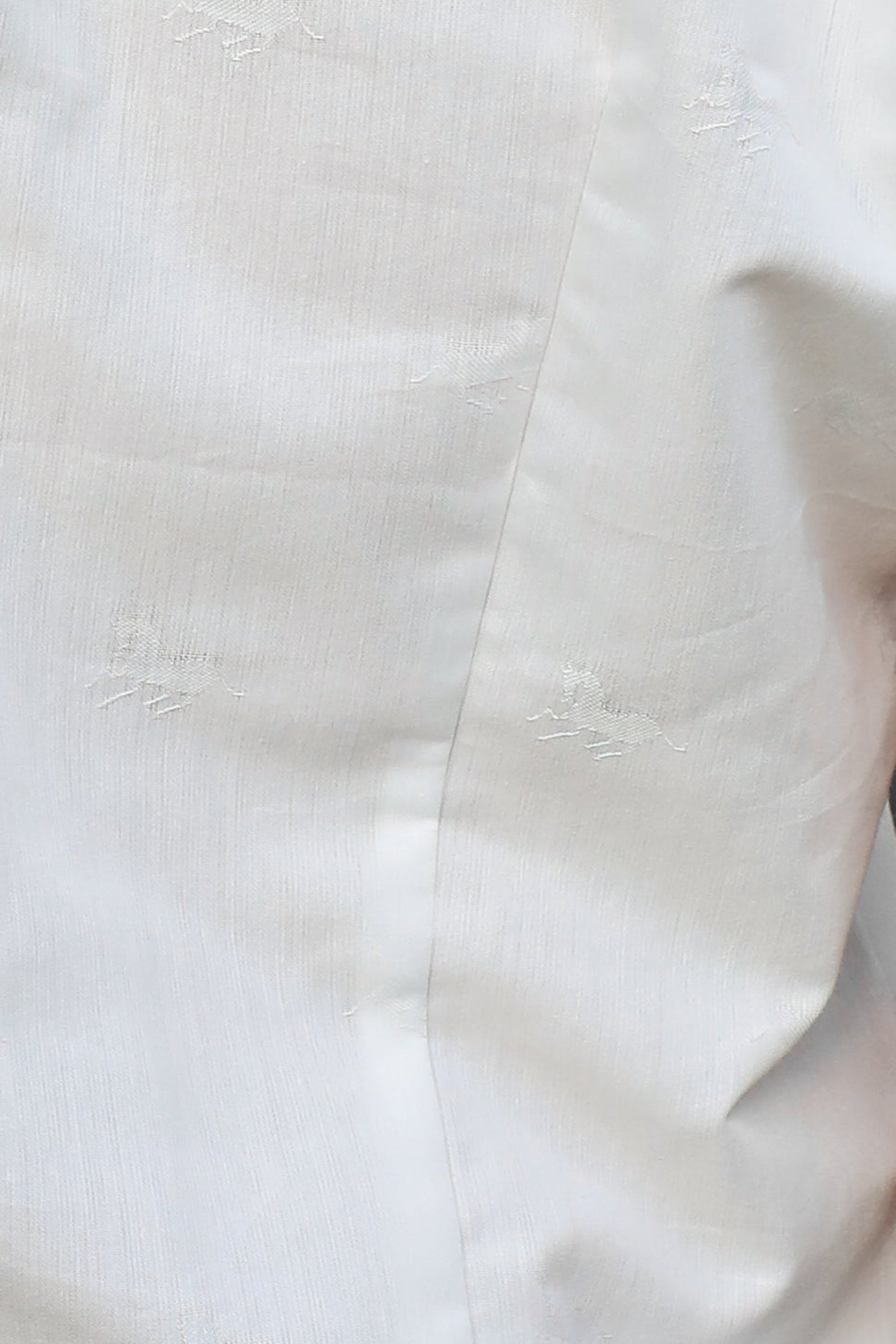 Close-up of a person wearing a white short-sleeve button-up shirt tucked into blue jeans with a brown belt.