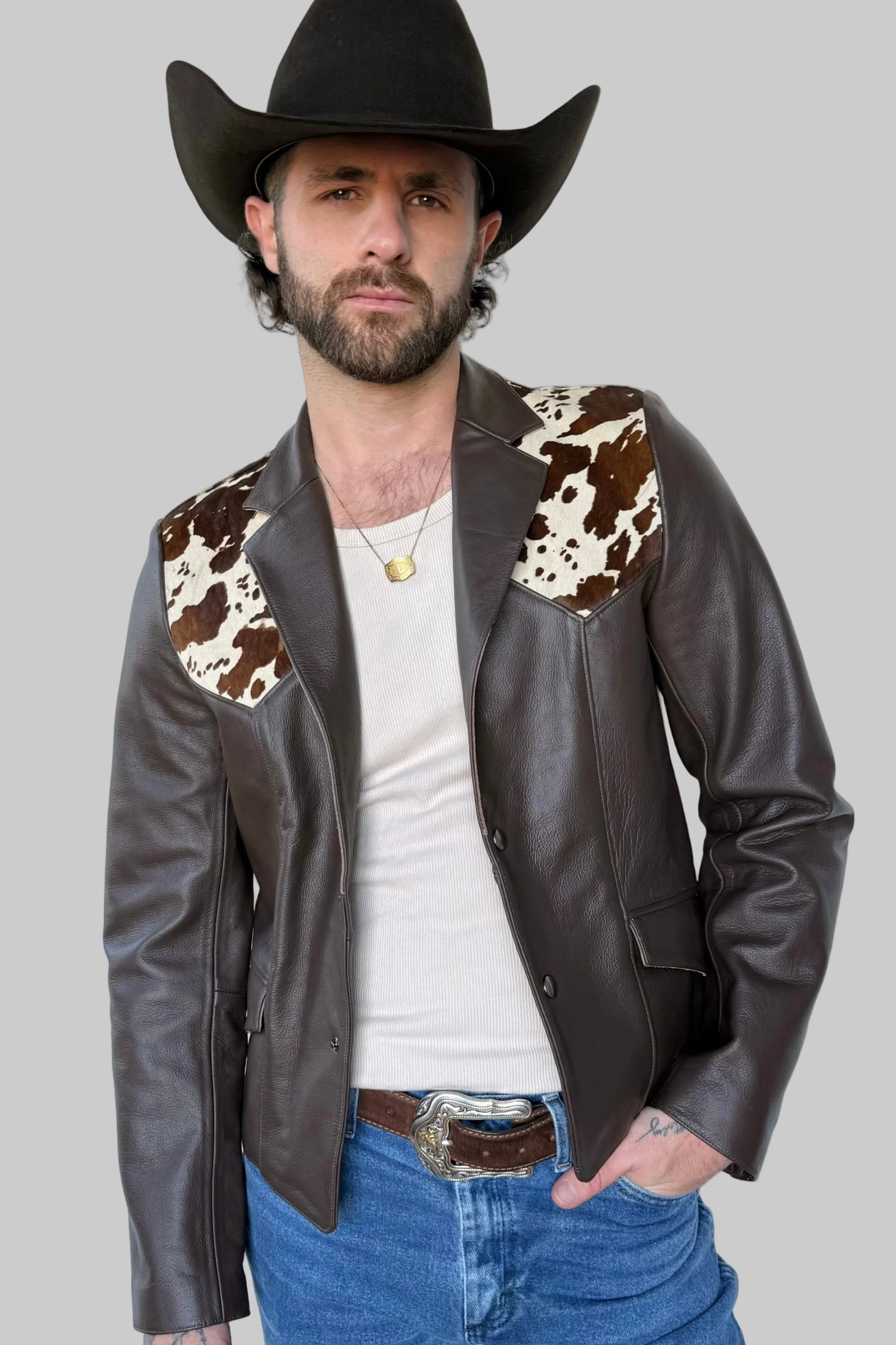 Man wearing a brown leather jacket with cowhide patches against a light background