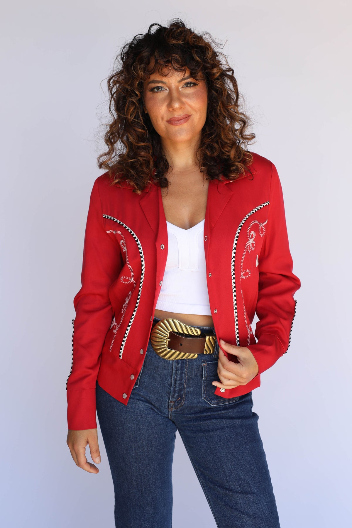 Woman wearing the H Bar C Bolero red cropped western jacket over a white tank with jeans, vintage inspired western wear.