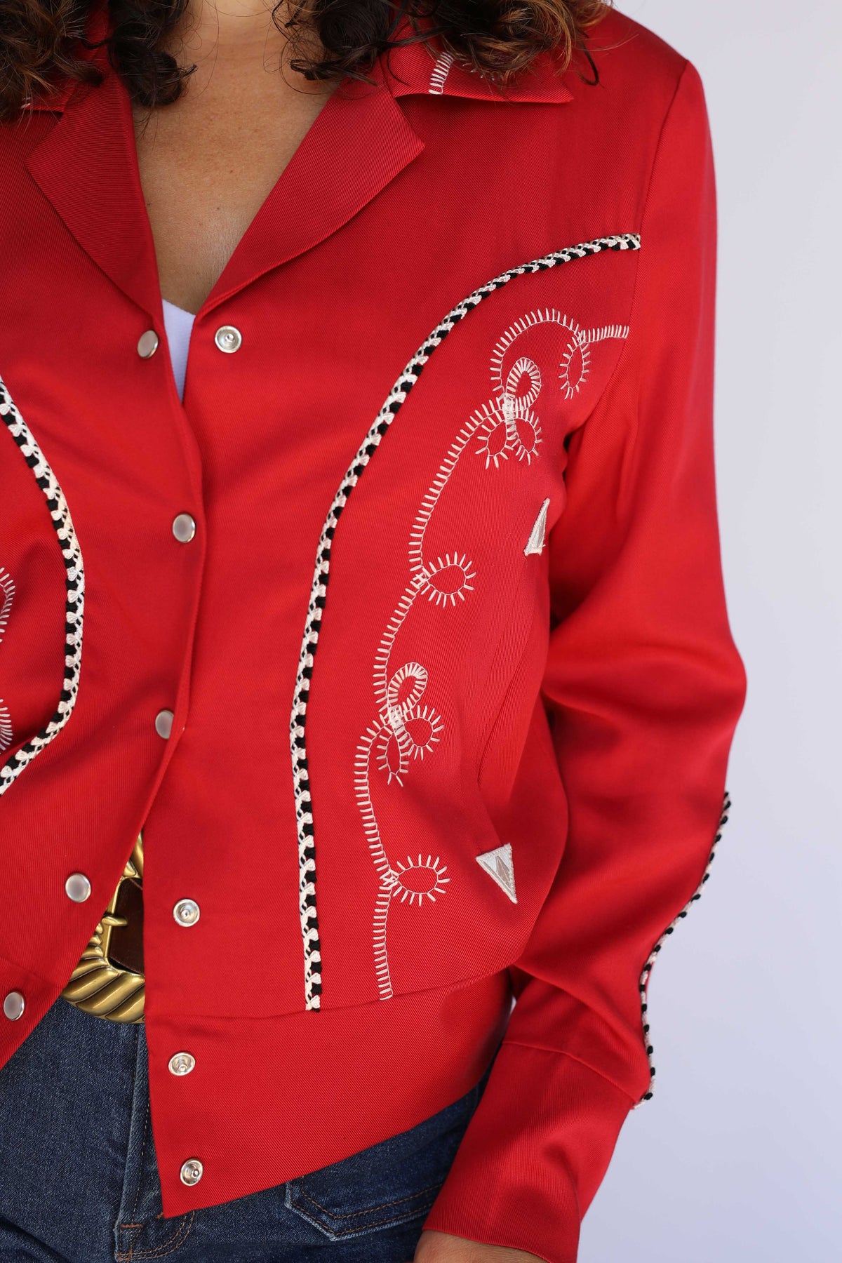 Close-up of the white piping and western details on the H Bar C Bolero red cropped jacket.