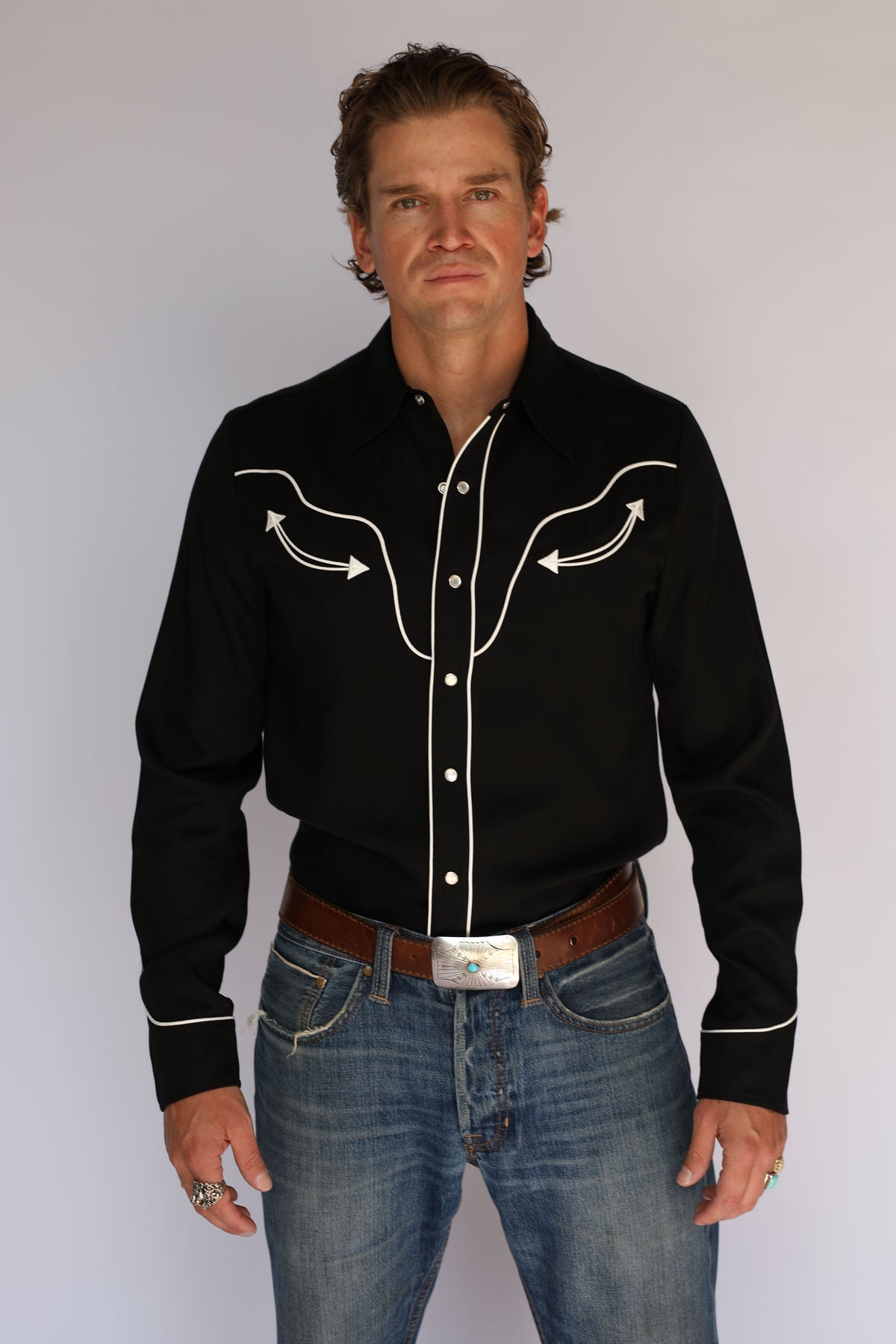 Man wearing the H Bar C San Fernando black western shirt, vintage inspired western wear with white piped yokes, arrow embroidery, and pearl snaps.