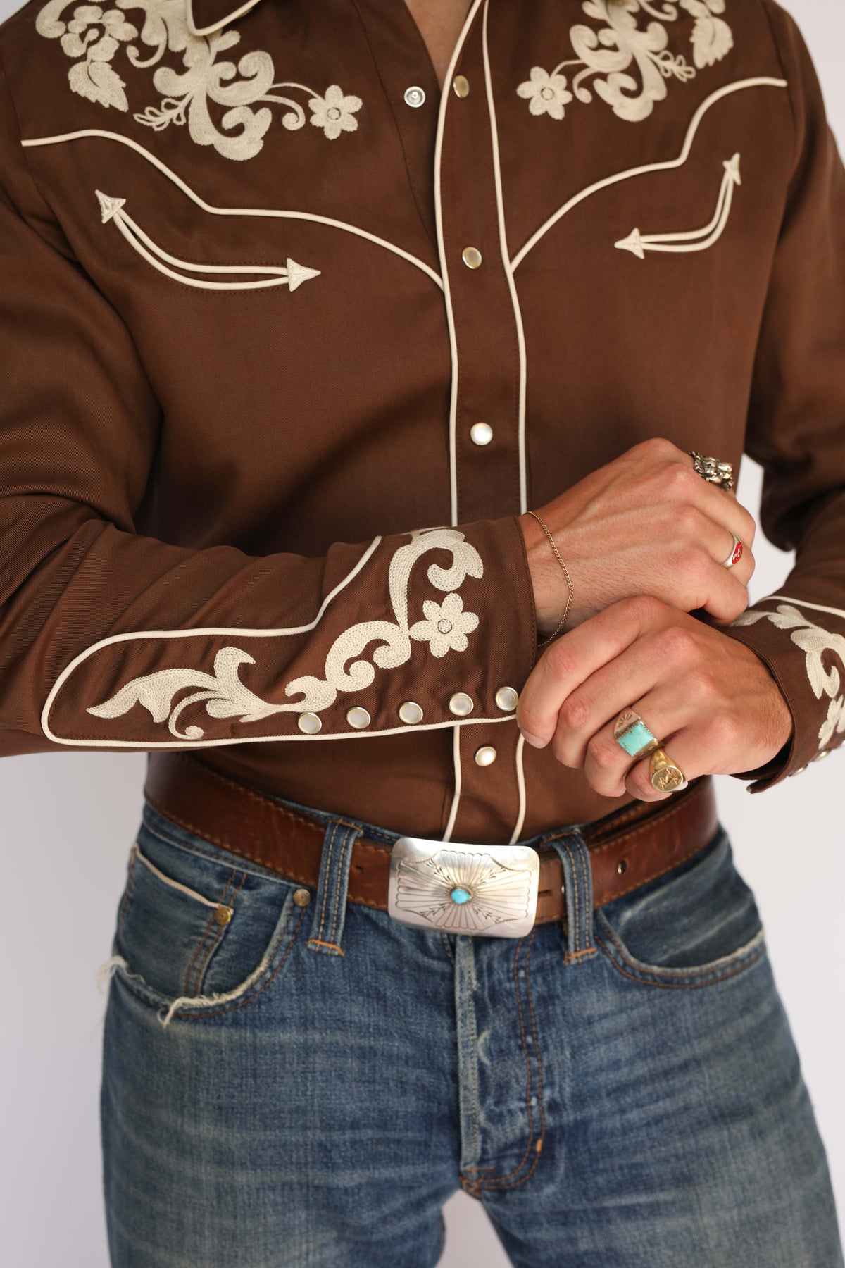 Close-up of the H Bar C Durango vintage western wear shirt front, showing chain stitch embroidery on the yoke, pearl snaps, and belt buckle.