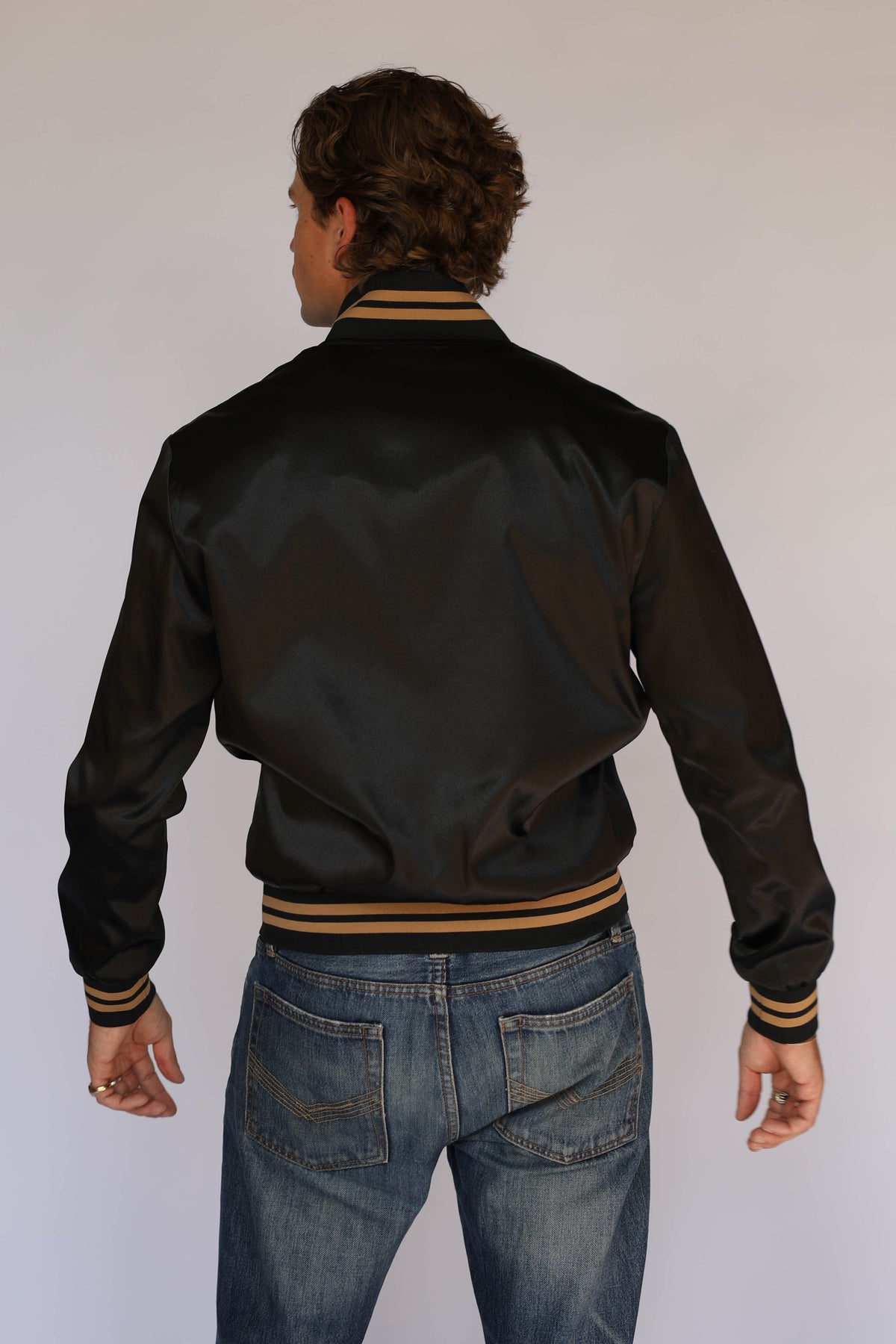 Back view of the H Bar C x Gibson J-200 Odessa black satin jacket, vintage inspired western wear with striped ribbed waistband and cuffs.