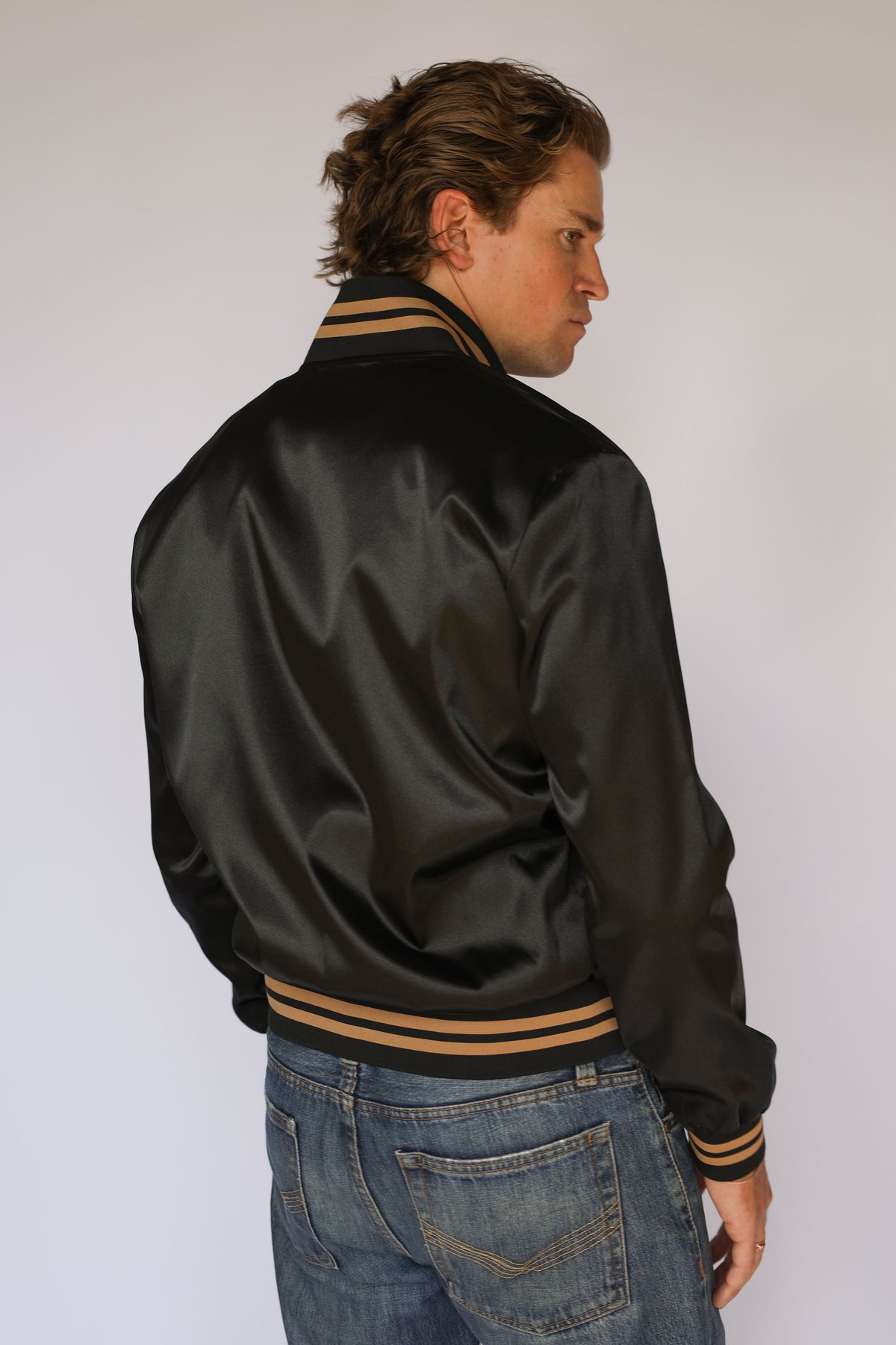 Side profile of the H Bar C x Gibson J-200 Odessa black satin jacket worn with jeans, vintage inspired western wear.