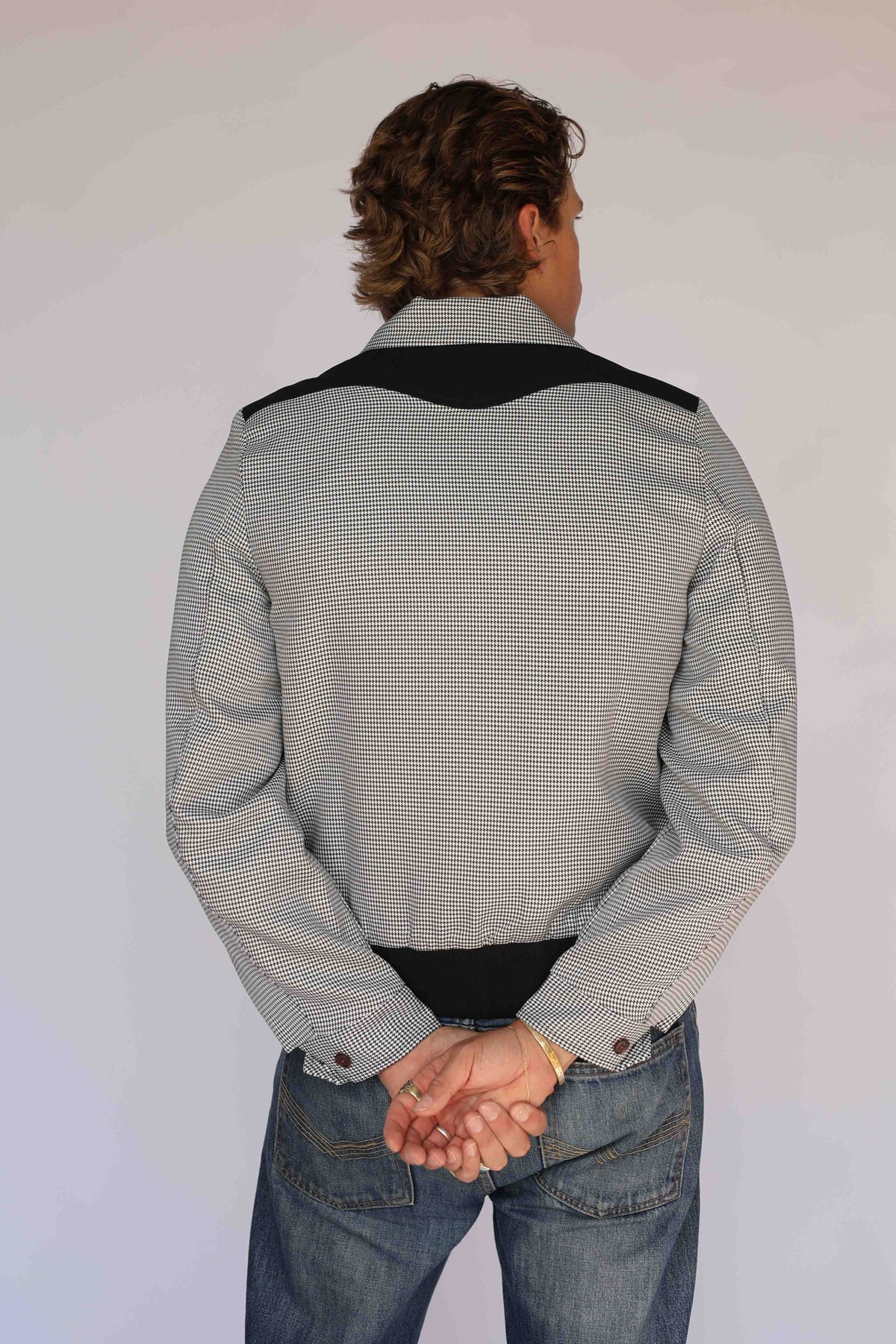 H Bar C Kentucky jacket in black houndstooth with black suede western yoke, zip front, and ribbed waistband, worn by a model