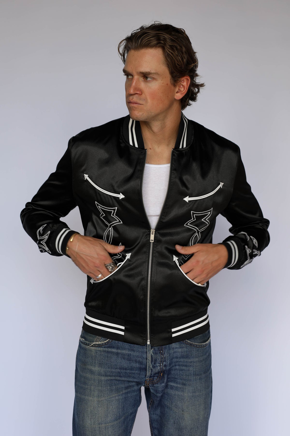 Three-quarter view of the H Bar C Odessa unisex tour jacket in black satin, vintage inspired western wear with zip front and black and white striped cuffs.