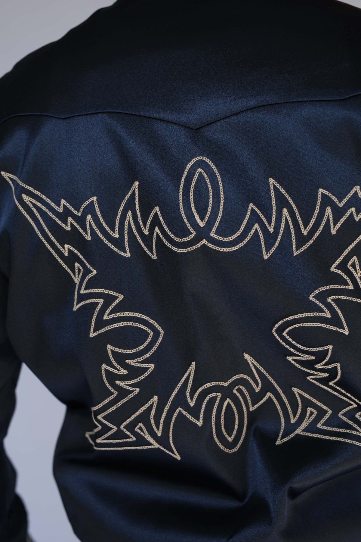 Close-up of the cream chain stitch embroidery on the back of the H Bar C Odessa navy satin tour jacket, a vintage western wear detail.