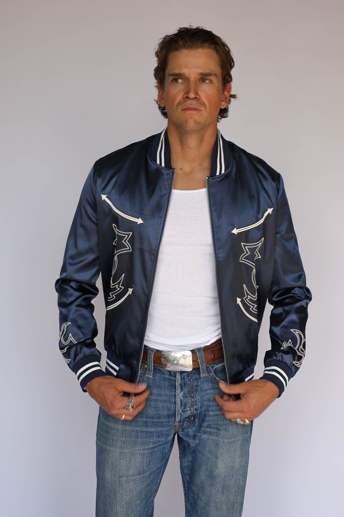 H Bar C Odessa unisex tour jacket in navy satin with zip front and navy and cream striped trim, vintage western wear worn with jeans.