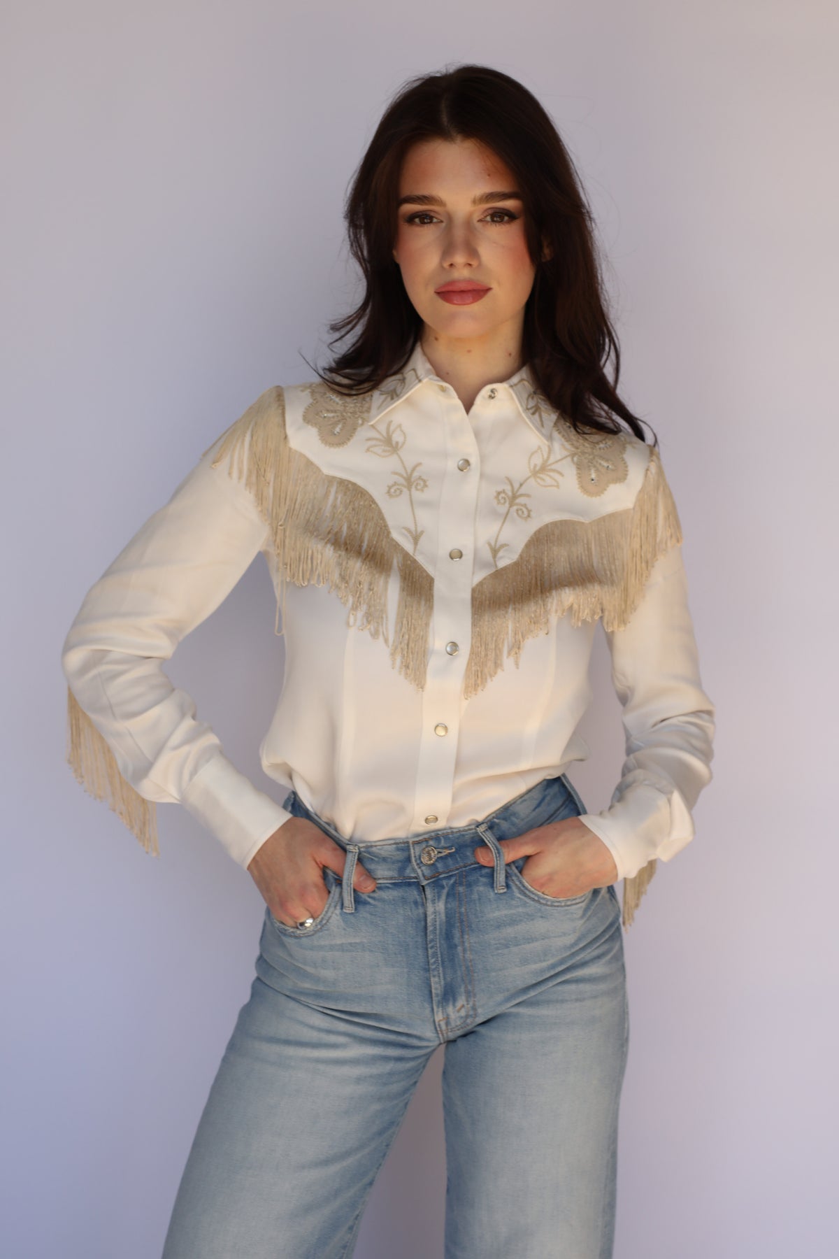 Woman in the H Bar C Taos women's white western shirt with fringe, styled with jeans.
