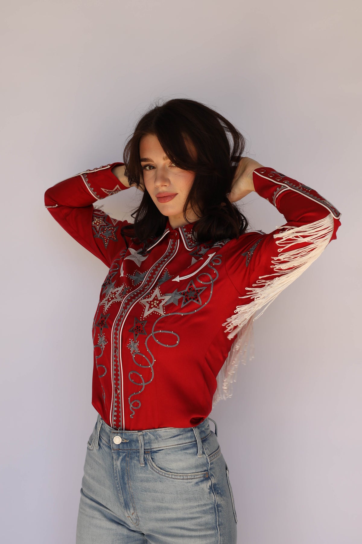 Model posing in the H Bar C Las Vegas red rhinestone and fringe western shirt, vintage inspired western wear.